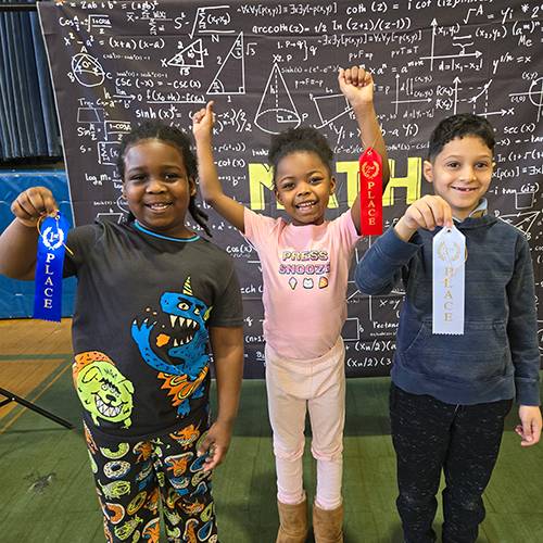 Three elementary students celebrating coming in 1st, 2nd and 3rd place in a school math competition